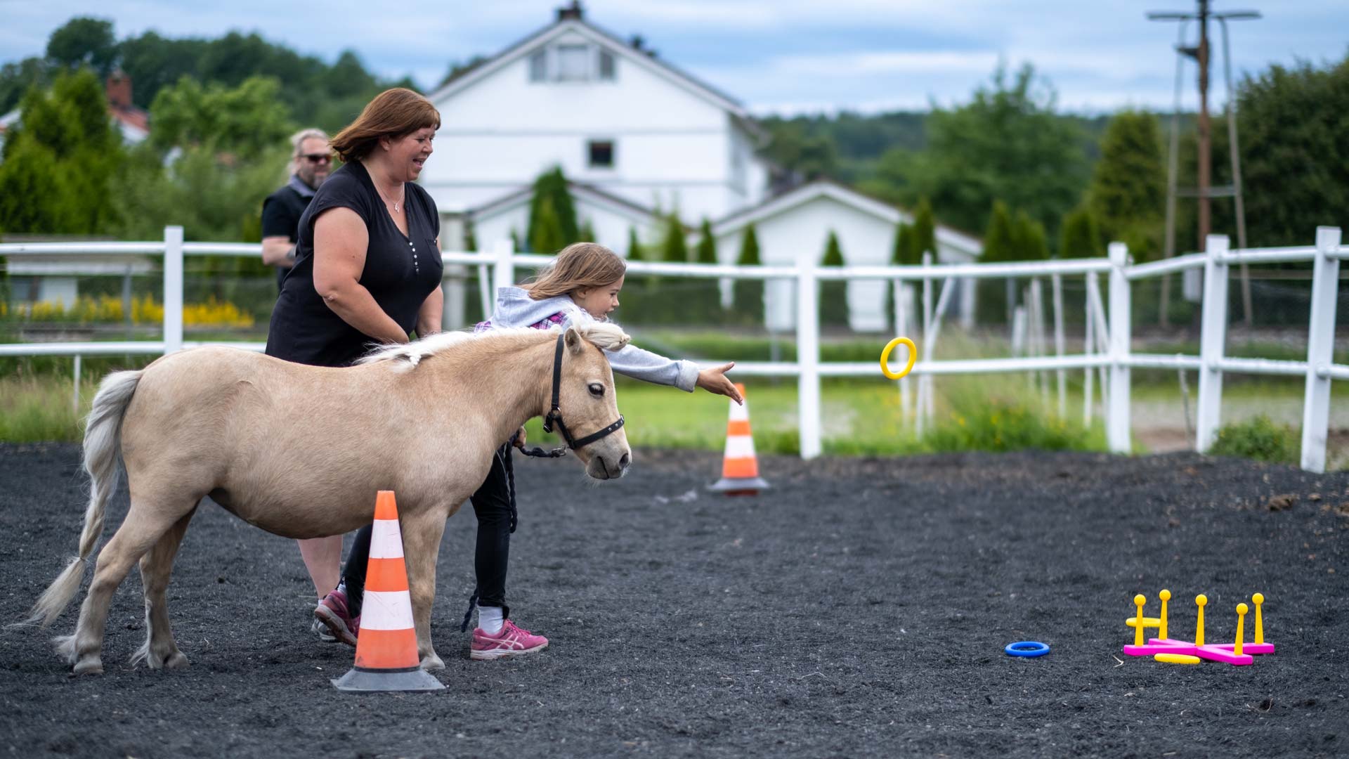 Barn kaster en ring fra hesteryggen med en voksen ved siden av på Hjørgunn